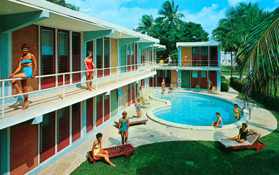 A vintage 60's era motel pool and coutyard with swimmers lounging. 